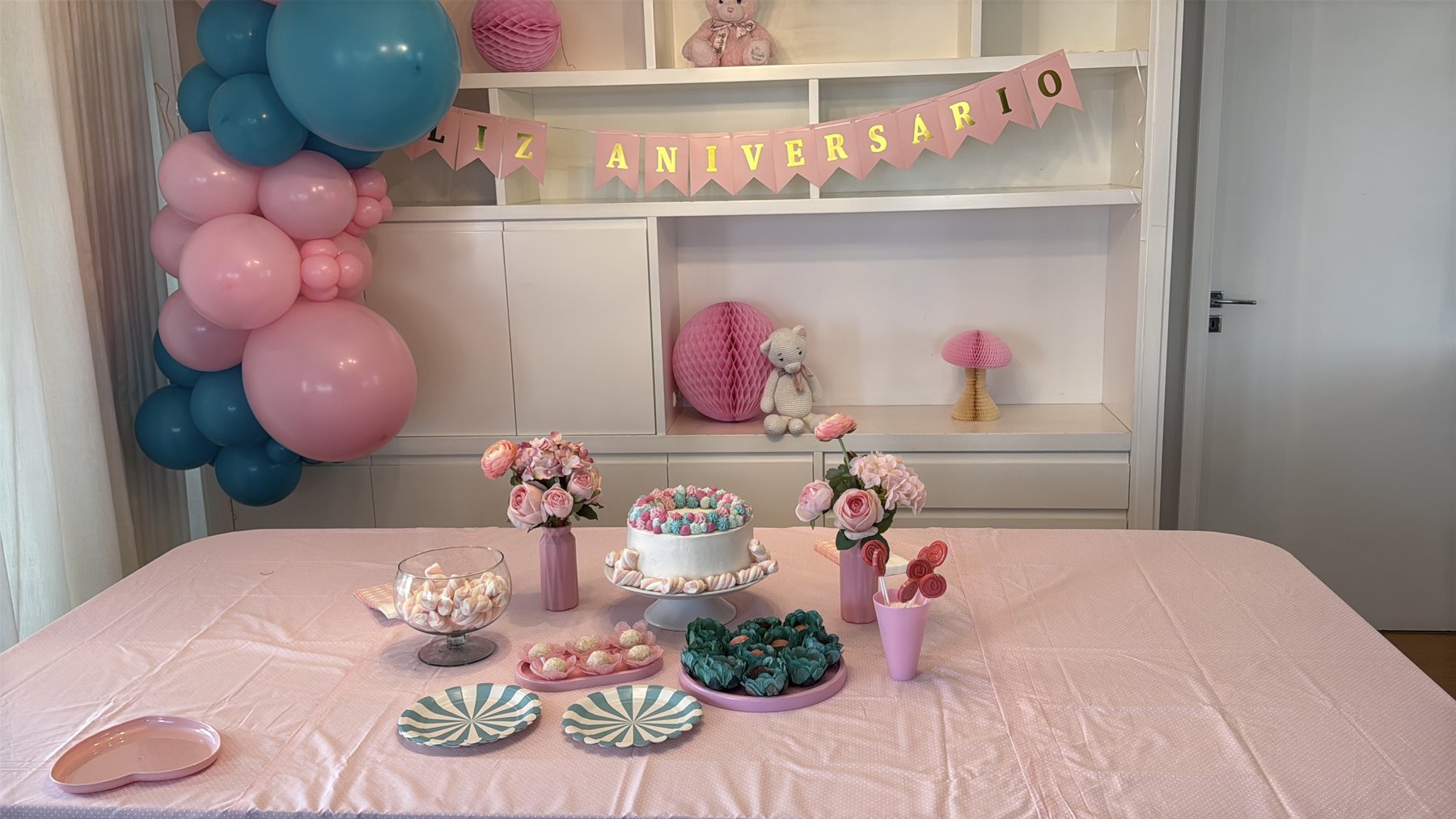 Mesa de festa infantil feita em casa com bolo, doces e flores